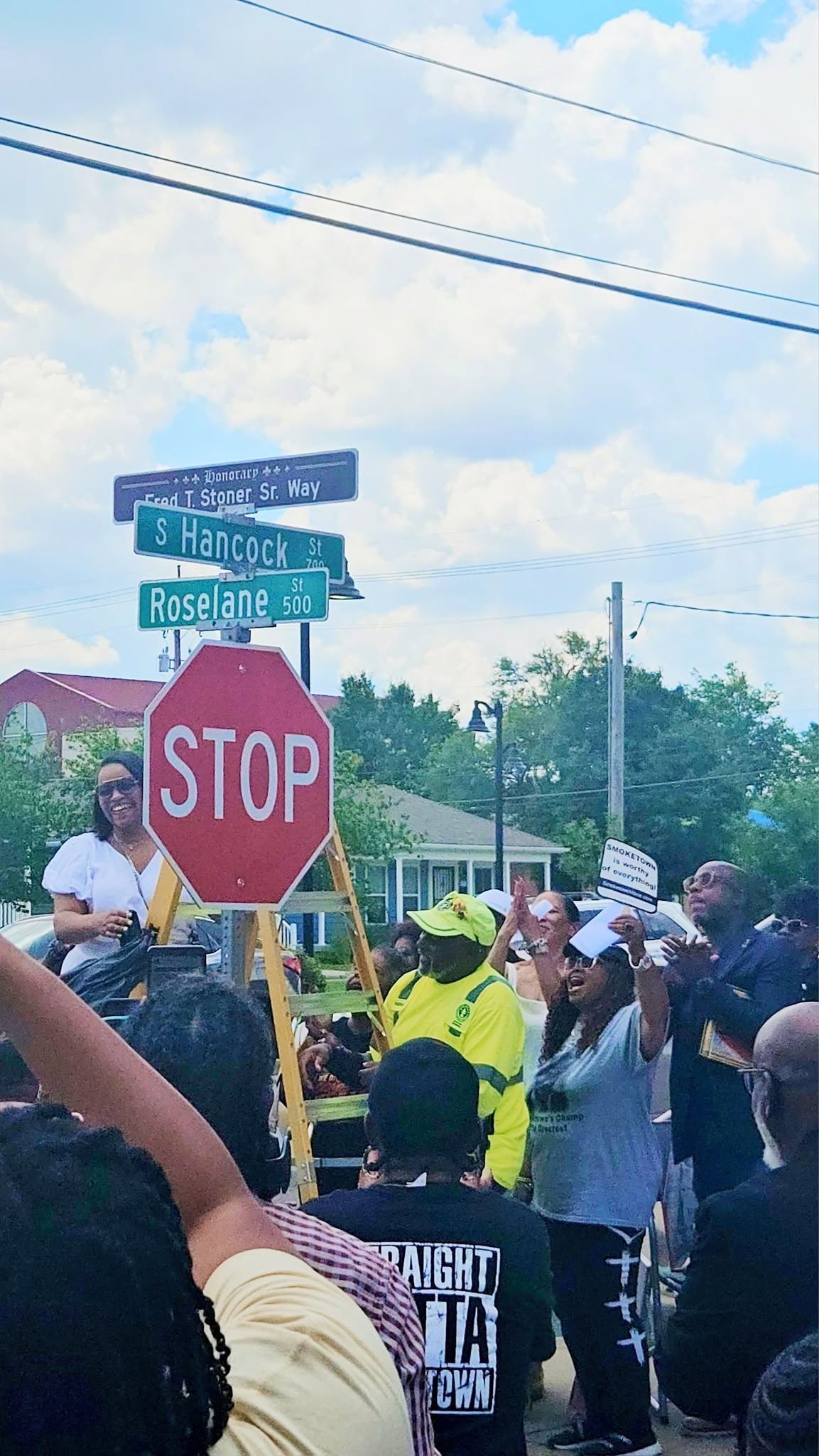 Community members cheering beneath the honorary street sign