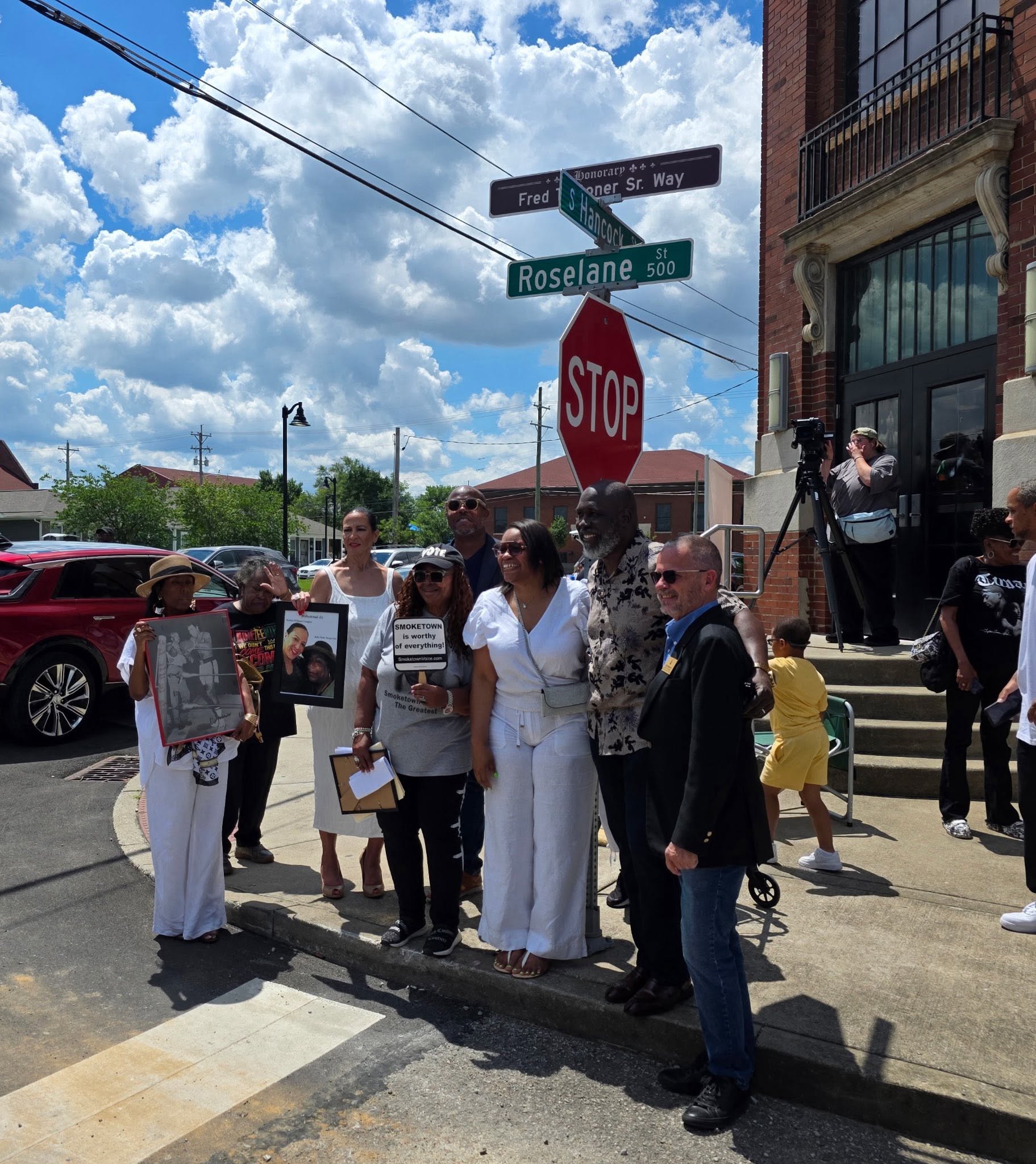 Family and community members gathered beneath the street signs